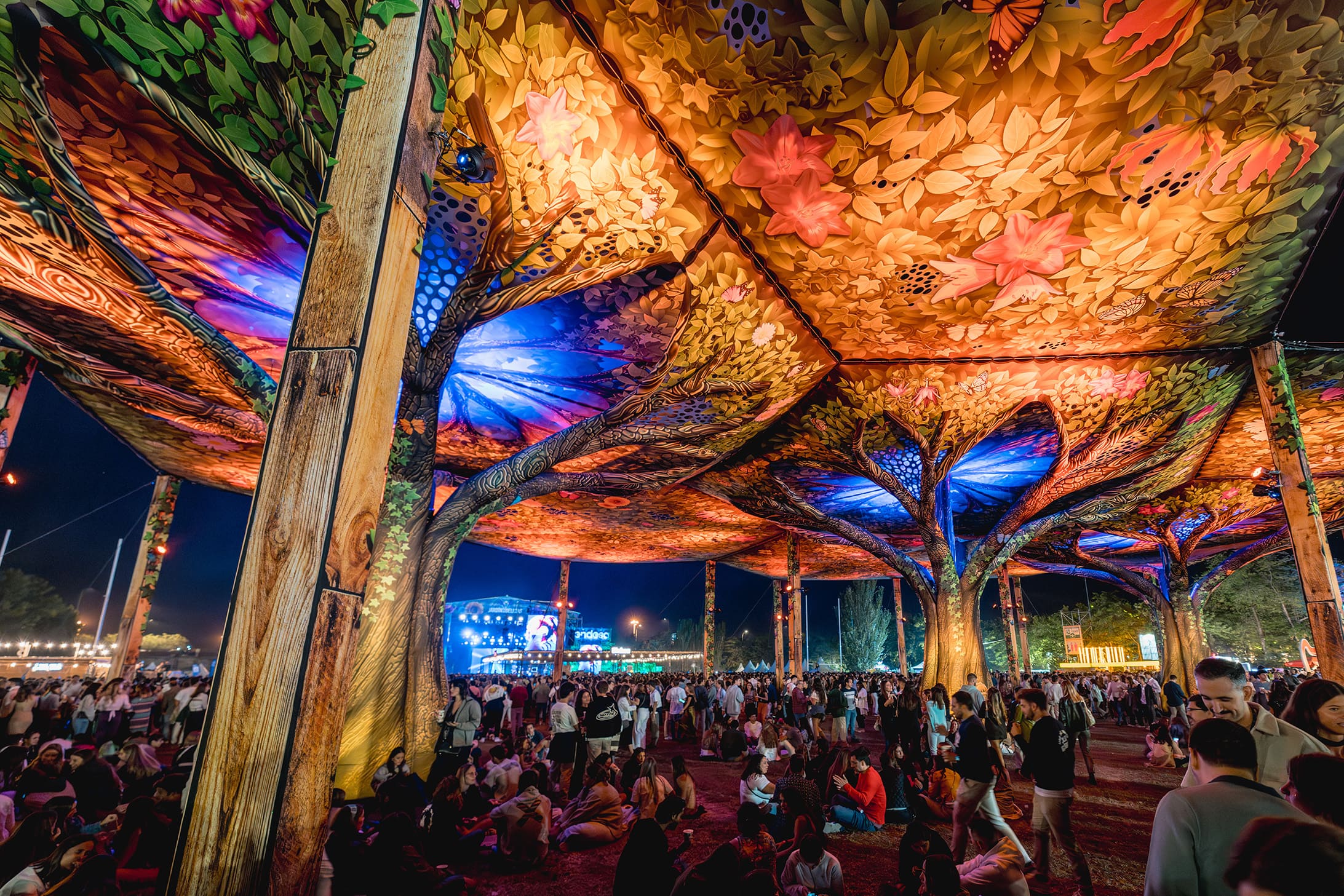 Zona decorativa iluminada de noche con público en el festival Jardín de las Delicias en Madrid